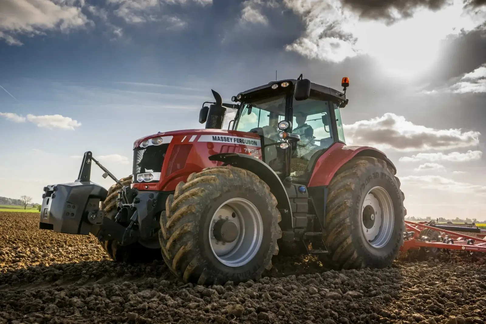 Massey Ferguson-traktor med redskap på ett fält